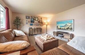A living room with a brown leather sofa, a wooden cabinet, a lamp, and a painting on the wall.