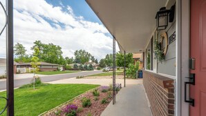 A residential street with a house featuring a covered porch, a brick wall, and a mailbox. - Golden Home in the Valley near Red Rocks (Golden)