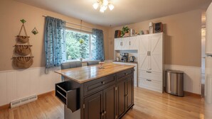 A kitchen with wooden cabinets, a central island, a window with curtains, and a ceiling light fixture. - Golden Home in the Valley near Red Rocks (Golden)