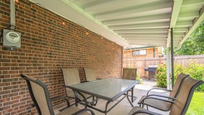 A covered patio with a brick wall, a table, and four chairs. - Golden Home in the Valley near Red Rocks (Golden)