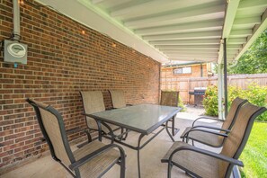 A covered patio with a brick wall, a table, and four chairs.