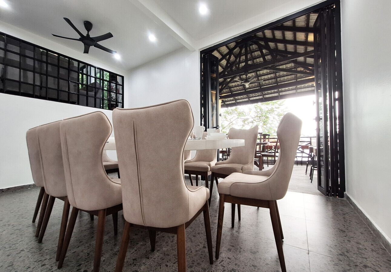 Un coin repas avec des chaises de couleur beige, une table blanche et un ventilateur de plafond.