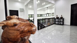 Un hall d’entrée avec un sol ciré, un escalier et une sculpture en bois décorative.