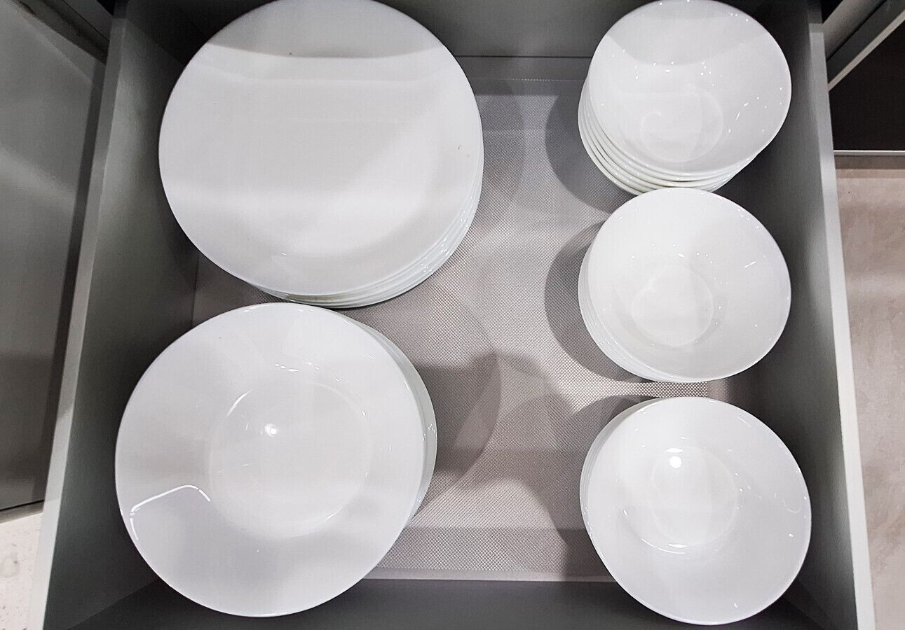 Un cajón con platos blancos de distintos tamaños.