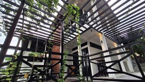 Un bâtiment moderne doté d’une structure en métal noir et agrémenté de plantes vertes.