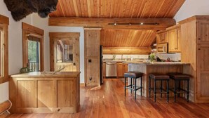 A rustic kitchen with wooden cabinets, a central island, and a ceiling fan. - Abode at Forest Edge, luxury log home, hot tub (Wilson)