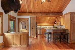 A rustic kitchen with wooden cabinets, a central island, and a ceiling fan. - Abode at Forest Edge, luxury log home, hot tub (Wilson)
