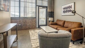 A furnished living room with a sofa, armchair, coffee table, and a desk. - Landing | Spectacular 2BD in Uptown (Memphis)