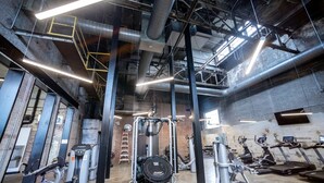 A gym with exercise equipment, a brick wall, and exposed ductwork. - Landing | Spectacular 2BD in Uptown (Memphis)