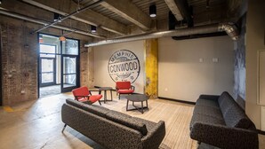 A spacious room with a large window, a wall mural, a sofa, and two red chairs. - Landing | Beautiful 2BD in Uptown (Memphis)