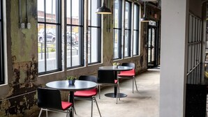 A café with round tables and red chairs, large windows, and exposed brick walls. - Landing | Beautiful 2BD in Uptown (Memphis)
