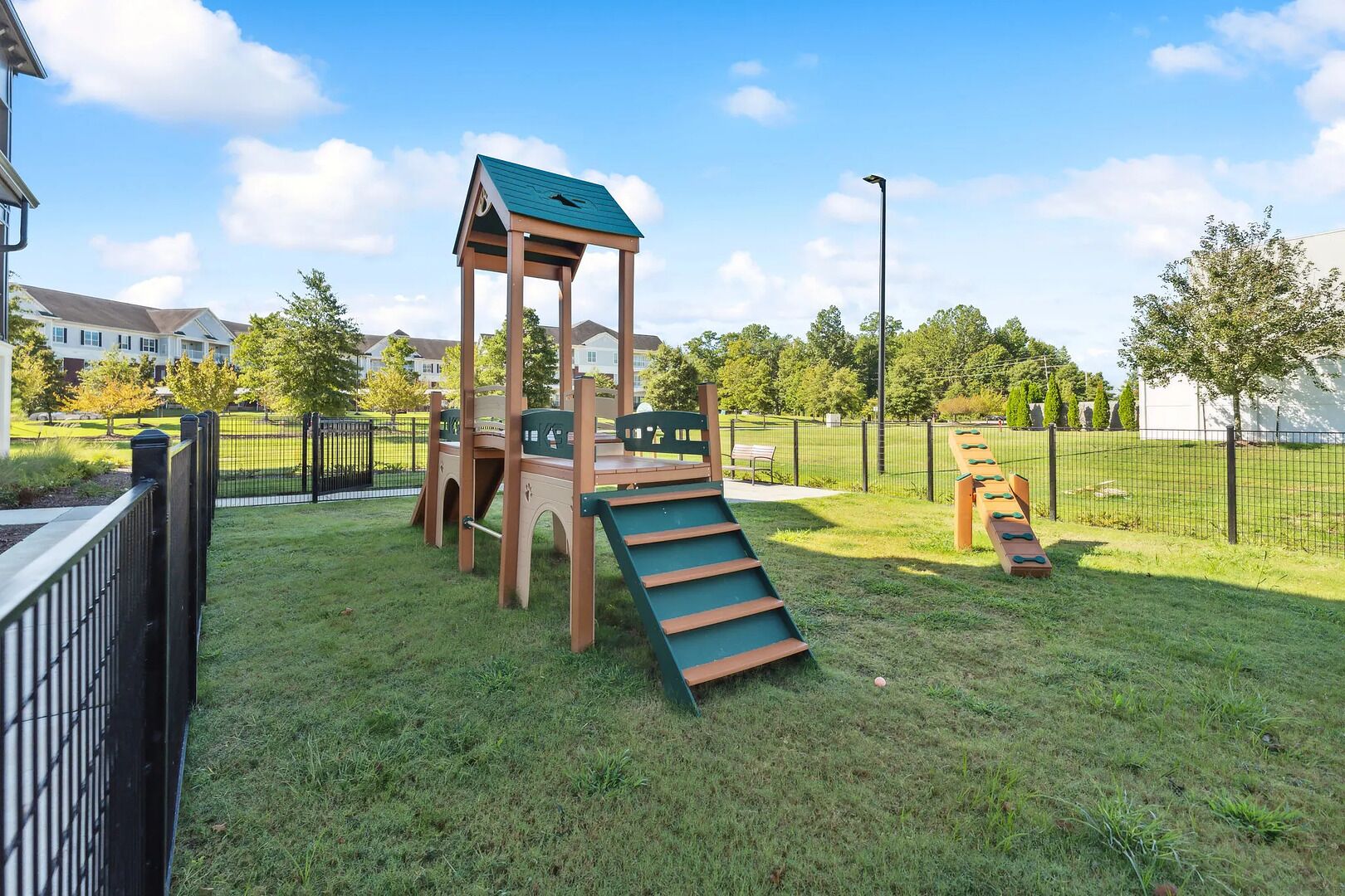 A playground with a climbing structure, a slide, and a swing set.