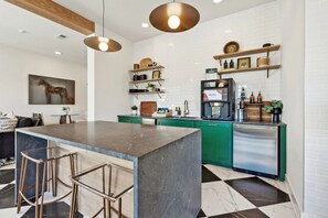 A modern kitchen with a central island, bar stools, a refrigerator, and a coffee machine. - Landing | Chic 2BD, Clubhouse (Memphis)