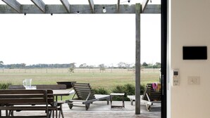 Un área de comedor al aire libre con vistas a un campo, bancos de madera y una mesa preparada para dos.