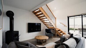 Una sala de estar moderna con chimenea, televisor, sofá, sillón y escalera.
