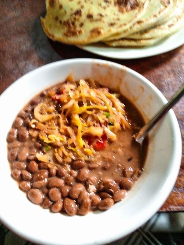 A bowl of bean soup with shredded cheese and a stack of flatbreads on a plate. - RG Hotel Mtongwe (Mombasa)