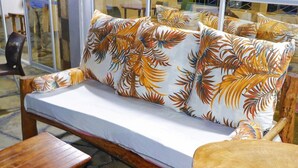 Een houten bank met een wit kussen en een sierkussen met bloemenprint.