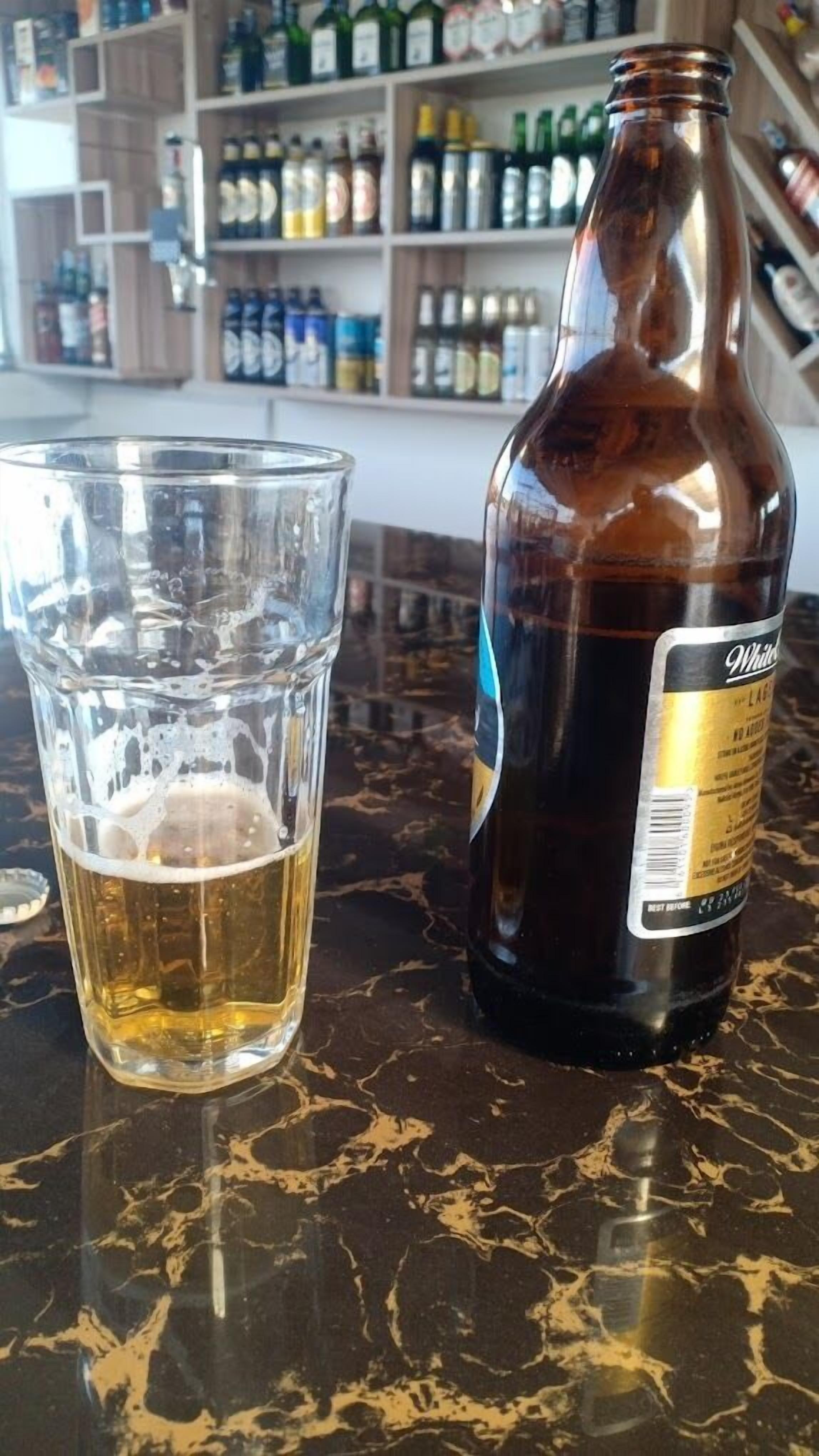 Una botella de cerveza y un vaso sobre el mostrador de un bar.