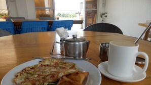 Een eettafel met een bord eten, een kop koffie en een metalen pan.
