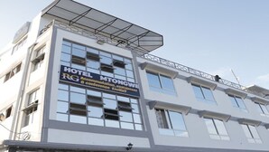 Een hotelgebouw met een bord waarop staat 'HOTEL MG TONGWE RG Accommodation & Restaurant'.