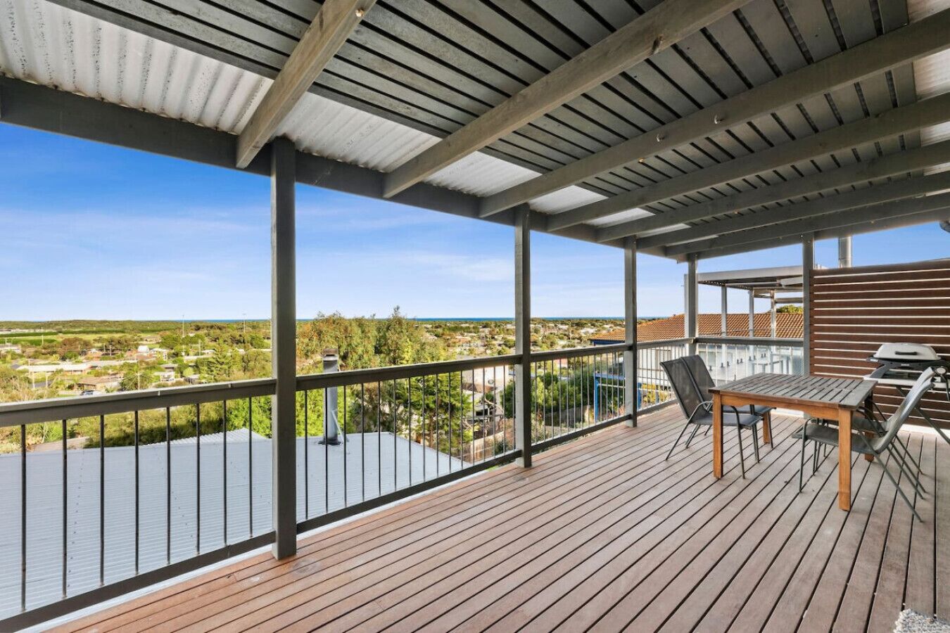 Une terrasse extérieure couverte, offrant une vue sur le paysage, avec une table et des chaises.