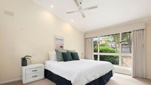 A bedroom with a bed, nightstand, and a window with curtains. - At the Hilltop - sleeps 10 - Pet friendly (Belmont)
