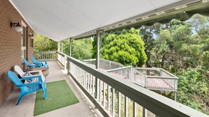 A covered balcony with a white railing, blue chairs, and a small table. - At the Hilltop - sleeps 10 - Pet friendly (Belmont)
