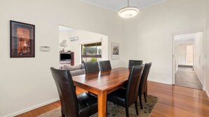 A dining area with a wooden table and chairs, a television, and artwork on the walls. - At the Hilltop - sleeps 10 - Pet friendly (Belmont)