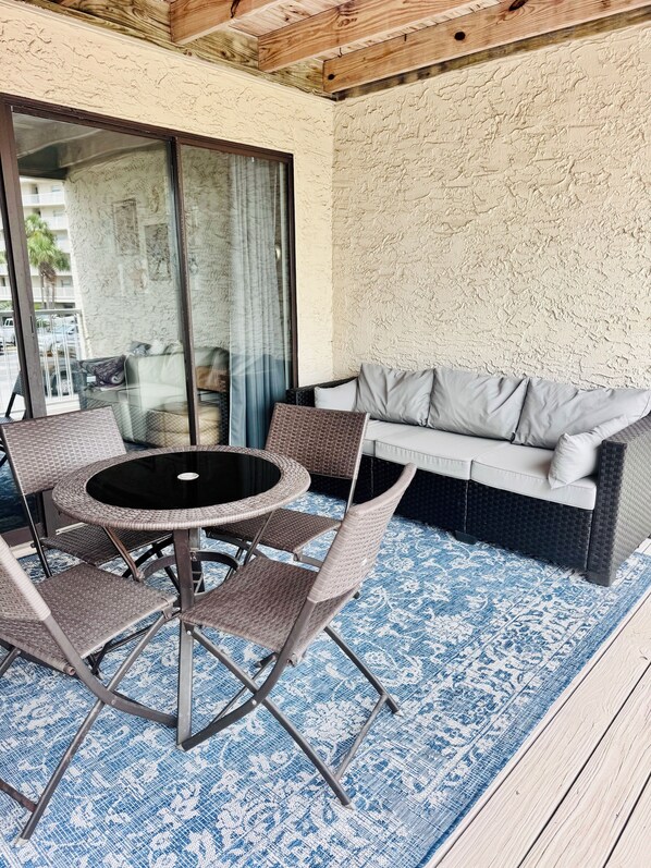 A patio area with a round table and chairs, a sofa, and a patterned rug. - Seaside Beach and Racquet Club: 2-Bedroom Condo Getaway in Orange Beach, Alabama (Orange Beach)