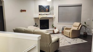 A modern living room with a fireplace, a ceiling fan, and a large window. - Spacious 4-bedroom house in beautiful Eaton (Eaton)