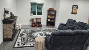 A living room with a fireplace, a large rug, a sofa, a side table, a bookshelf, and a window. - Spacious 4-bedroom house in beautiful Eaton (Eaton)