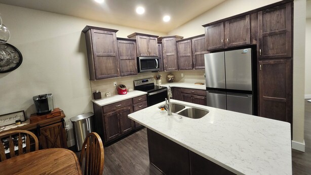 A modern kitchen with dark wooden cabinets, stainless steel appliances, a marble countertop, and a built-in sink. - Spacious 4-bedroom house in beautiful Eaton (Eaton)