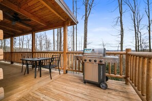 Una terraza techada con una parrilla, una mesa y sillas.