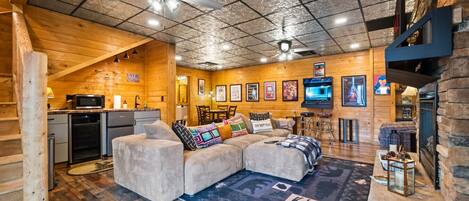 A cozy cabin interior with a wooden interior, a sofa, a television, and a fireplace.