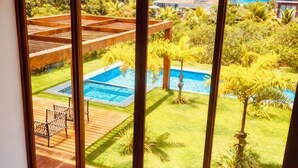 Ein Zimmer mit großen Fenstern mit Blick auf einen Pool und einen Garten.