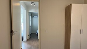 En hall med en garderob, en dörr som leder till ett annat rum och en lampa i taket.