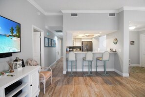 Una cocina moderna con una isla central, taburetes de bar y un televisor de pantalla plana montado en la pared.