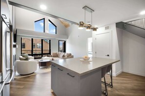 A modern kitchen with a large island, a dining area with a sofa and chairs, and a view of the outside.