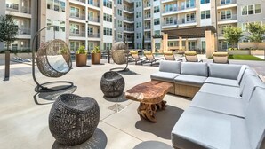 Een terras op het dak met buitenmeubels, waaronder een bank, stoelen en een hangstoel.