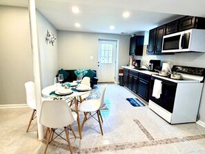 A dining area with a round table, chairs, and a kitchen with a stove and microwave.