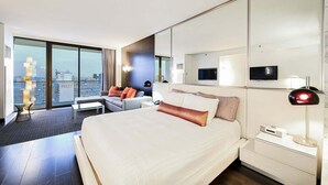Una habitación de hotel moderna con una cama grande, un sofá, un escritorio y vistas a la ciudad.