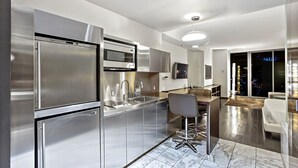 Una cucina moderna con elettrodomestici in acciaio inossidabile, un angolo bar e vista sulla città di notte.