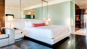 A modern hotel room with a large bed, a bedside table with a lamp, a chair, and a large mirror. - SVS: Strip View Studio | Open Balcony | Resort Amenities | Palms Place (Las Vegas)