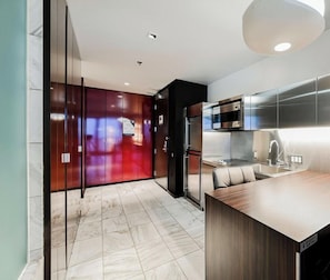 A modern kitchen with a marble floor, stainless steel appliances, and a wooden island.