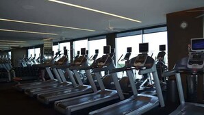 A gym with multiple treadmills and exercise equipment, large windows, and a modern ceiling design. - SVS: Strip View Studio | Open Balcony | Pool & Gym Access | Palms Place (Las Vegas)