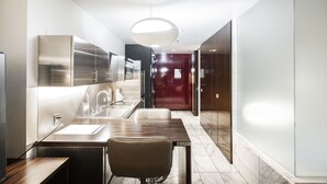 Et moderne køkken med rustfrie hårde hvidevarer, en marmor bordplade og en hængende lampe.