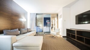 En moderne stue med sofa, fjernsyn og glasdør til en balkon.