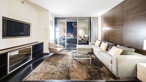 Ein modernes Wohnzimmer mit einem Flachbildfernseher, einer Couch, einem Couchtisch und einem großen Fenster mit Blick auf die beleuchtete Stadt bei Nacht.