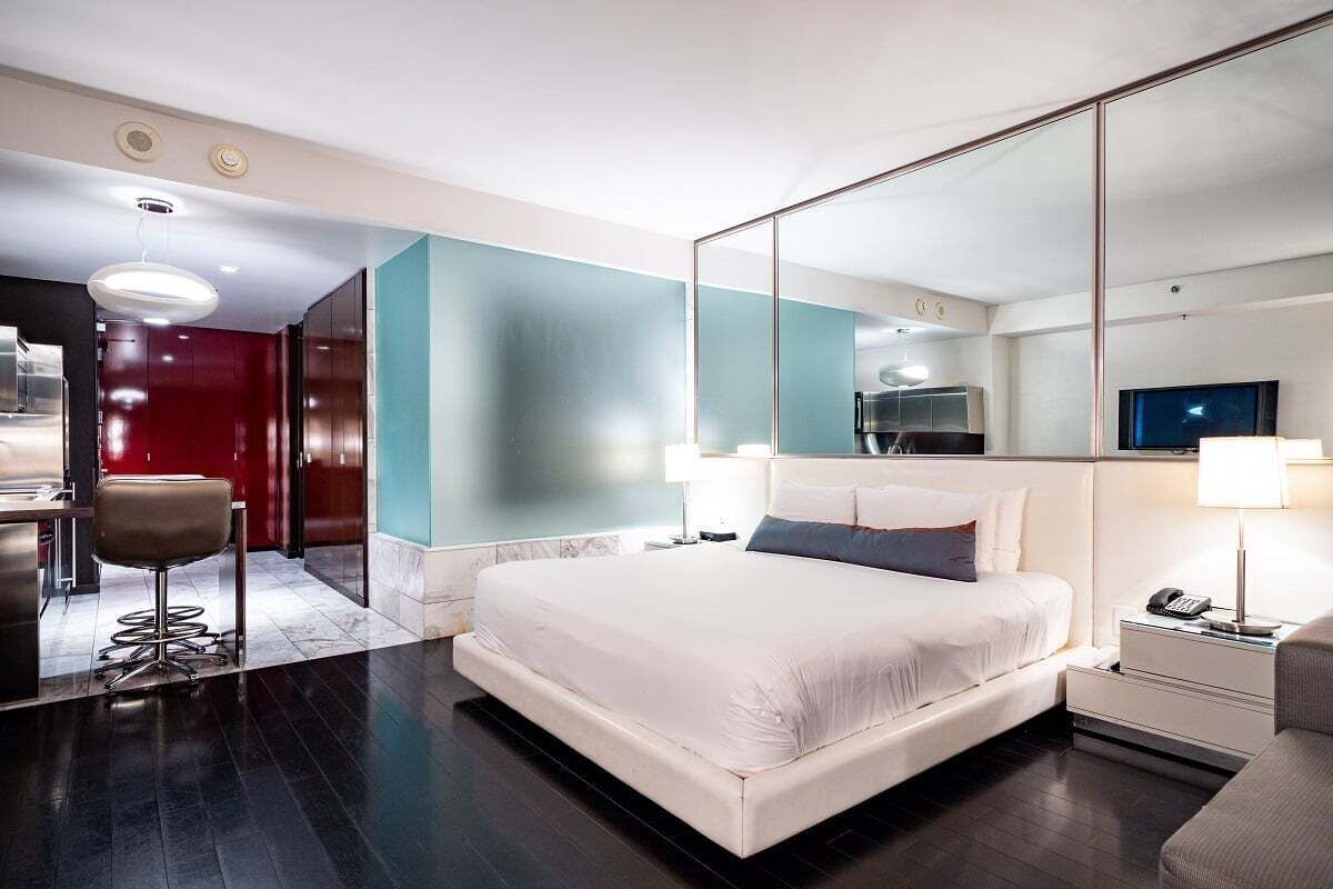 Une chambre d’hôtel moderne équipée d’un grand lit, d’un bureau, d’une chaise, d’un miroir et d’une télévision.