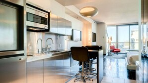 A modern kitchen with stainless steel appliances, a dining area with a high table and chairs, and a large window offering a city view. - SVS: Strip View Studio | Open Balcony | Resort Pool | Palms Place (Las Vegas)
